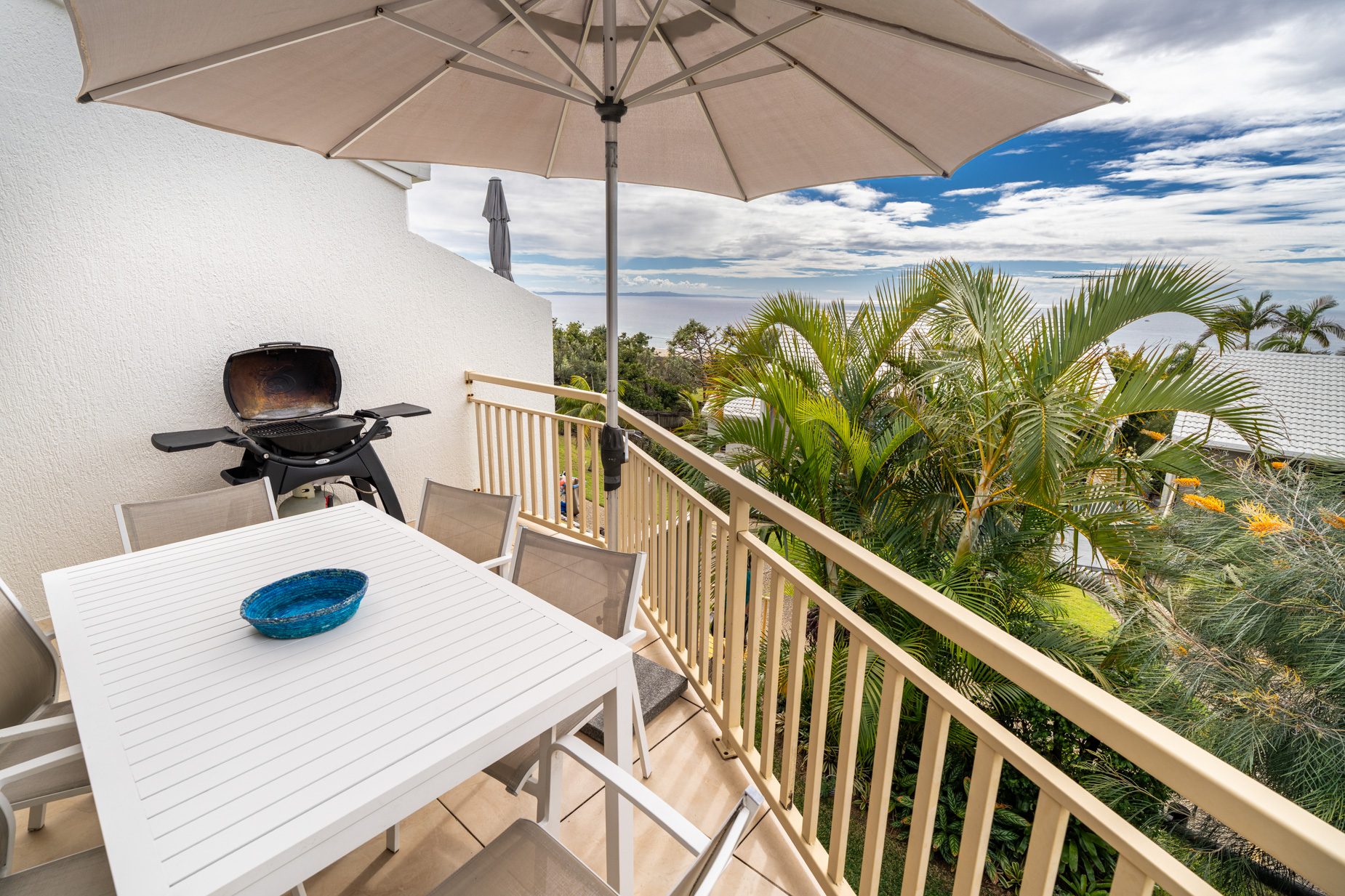 The private balcony of a Deluxe Ocean villa, with outdoor table and chairs among the palms