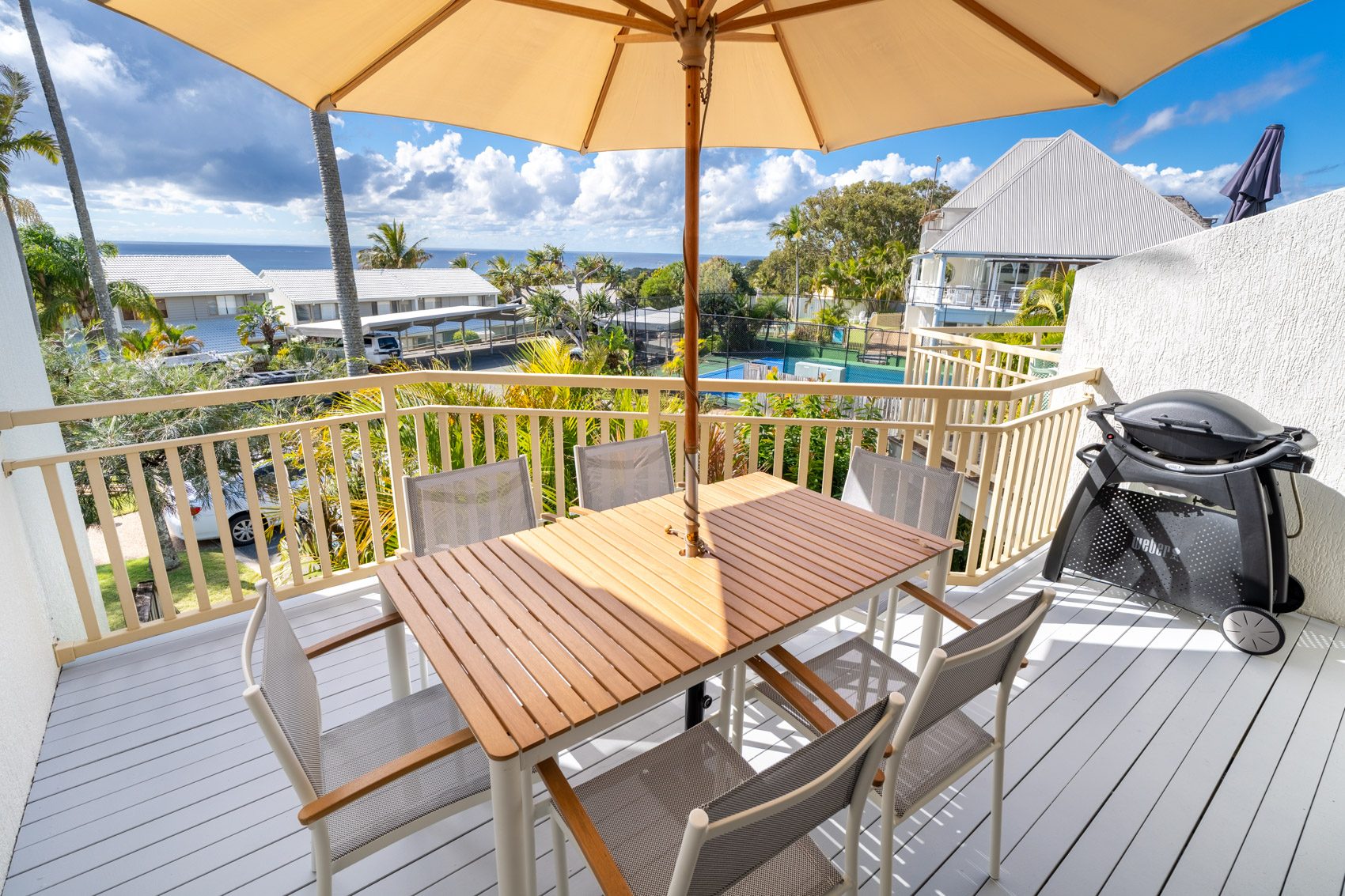 The private balcony of a Deluxe Ocean villa, with outdoor table and chairs among the palms