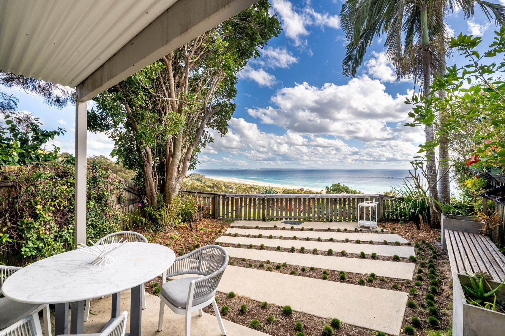The covered patio of a Prestige Headland Ocean villa, looking across the garden to the ocean