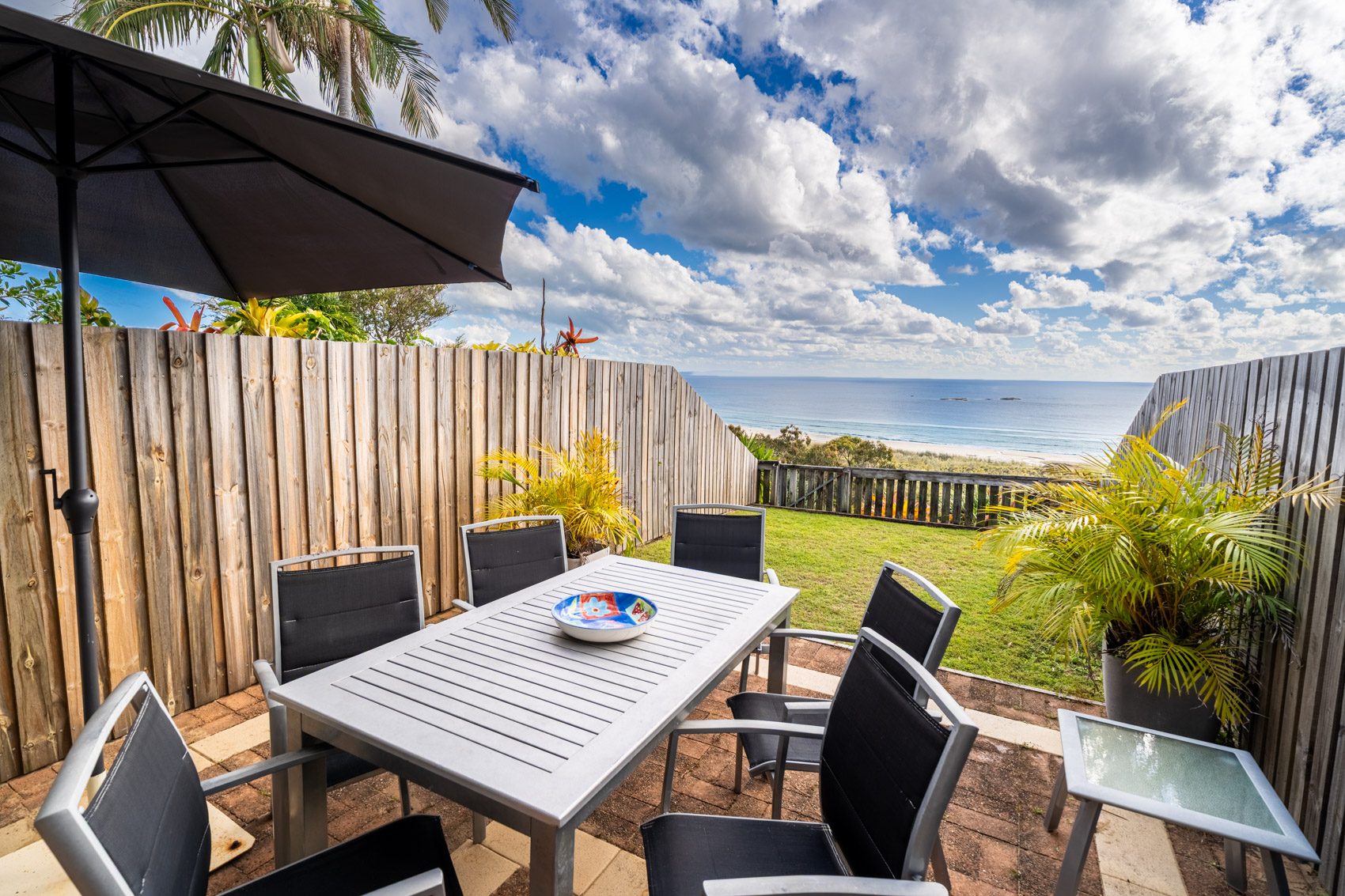 The private deck of a Premium Headland Ocean villa, with outdoor dining looking over the headland to the ocean