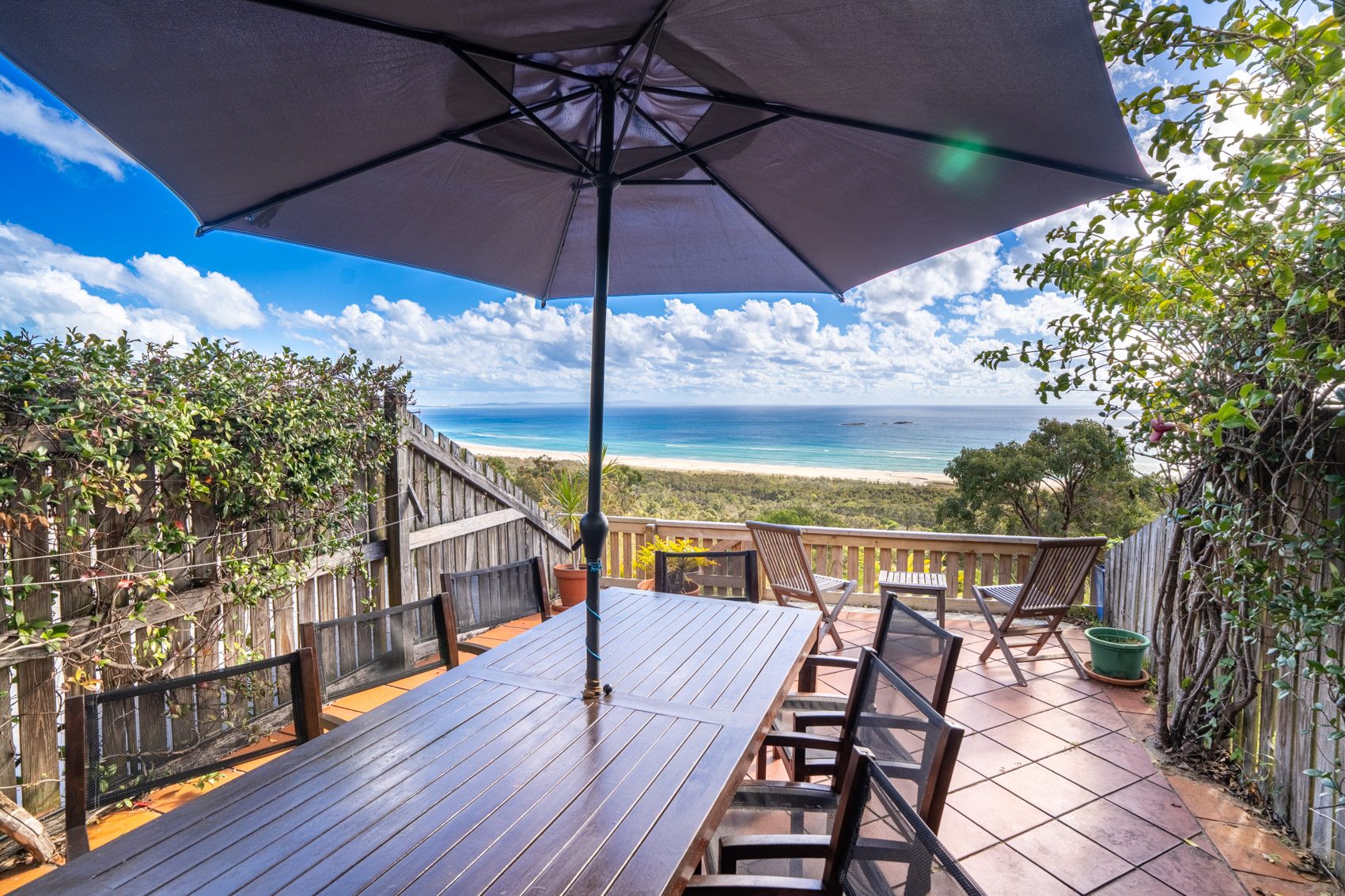 The private deck of a Premium Headland Ocean villa, with outdoor dining looking over the headland to the ocean