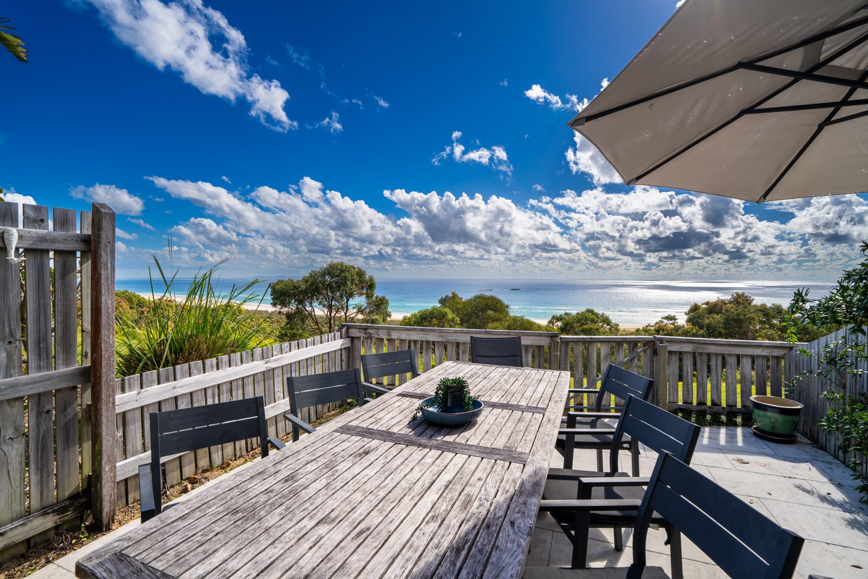 The private deck of a Premium Headland Ocean villa, with outdoor dining looking over the headland to the ocean