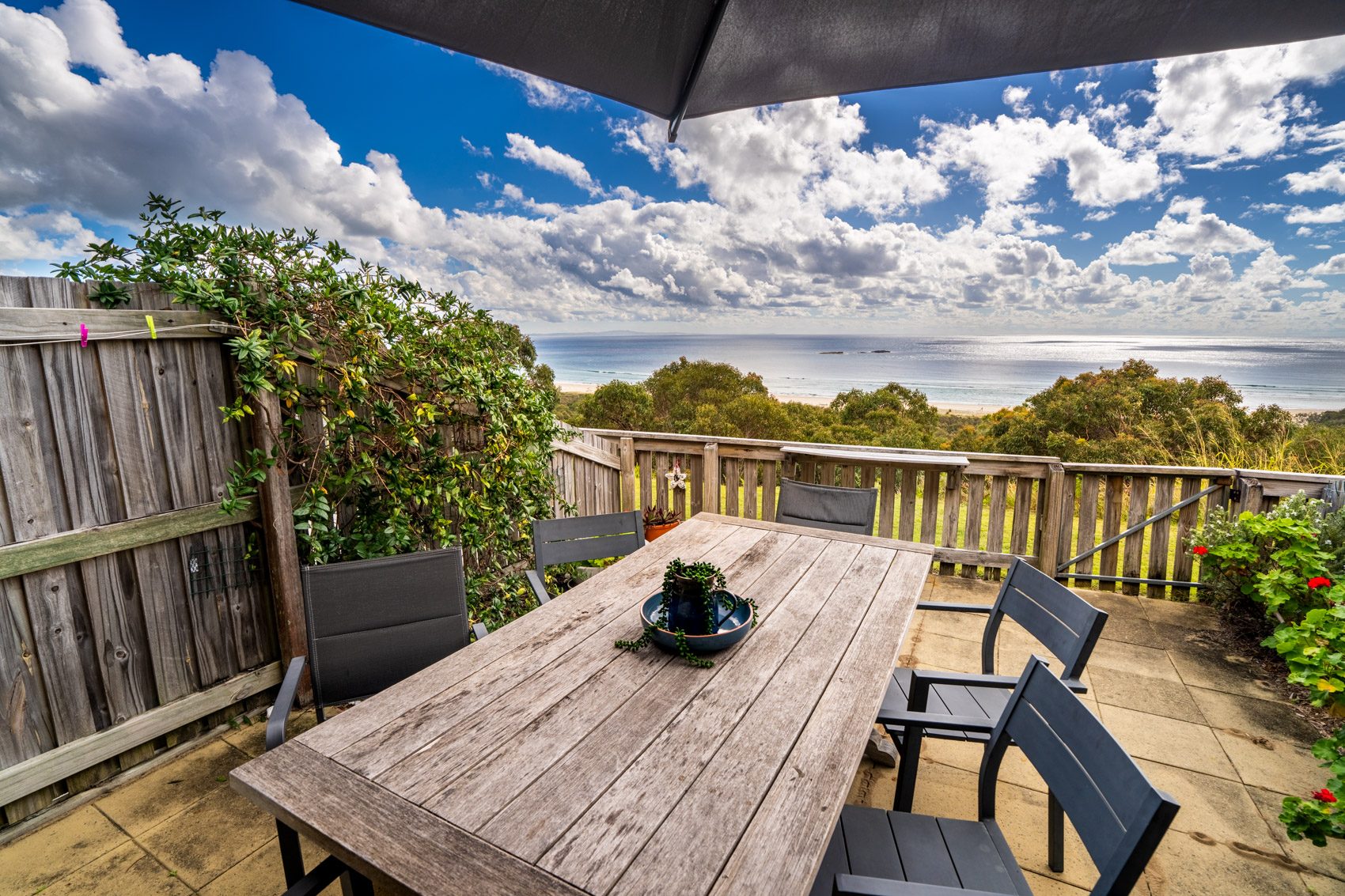 The private deck of a Premium Headland Ocean villa, with outdoor dining looking over the headland to the ocean