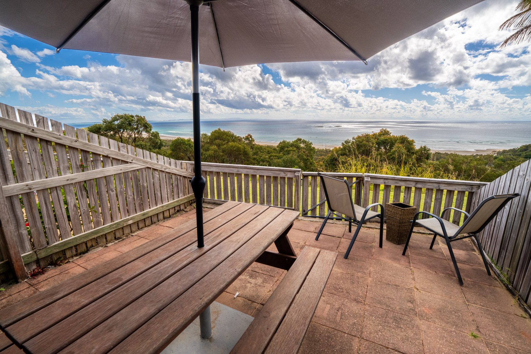The private deck of a Premium Headland Ocean villa, with outdoor dining looking over the headland to the ocean