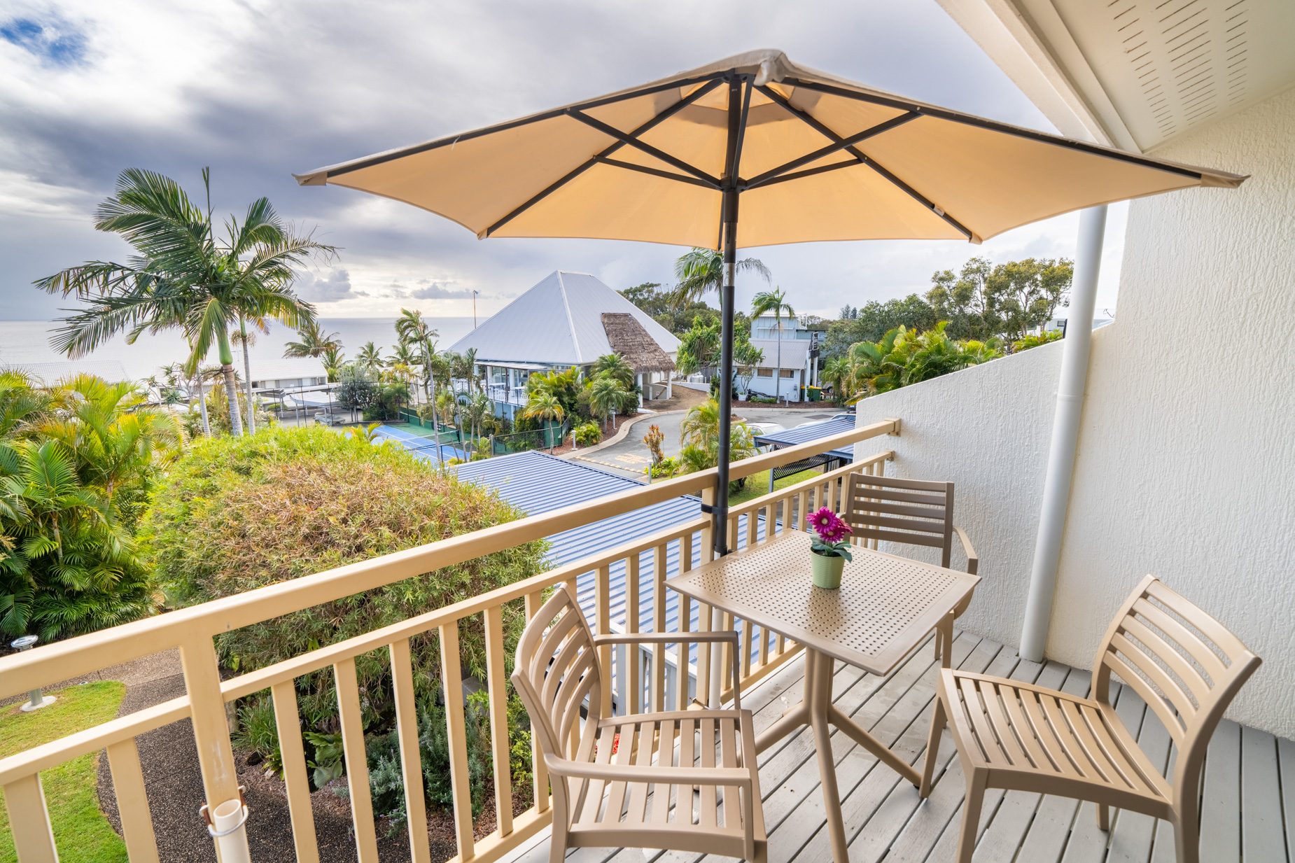 The private balcony of a Standard Ocean villa, with outdoor table and chairs among the palms
