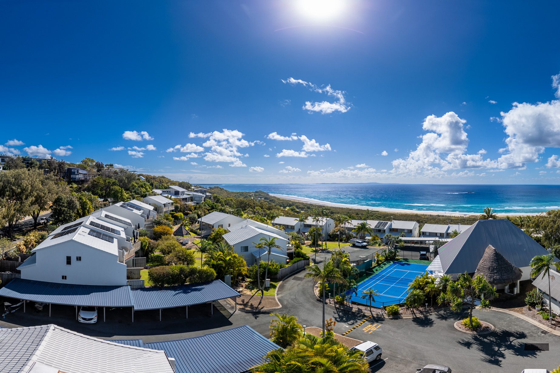 Looking out from behind Pandanus Palms Resort over the villas and the tennis court to the beach and the ocean