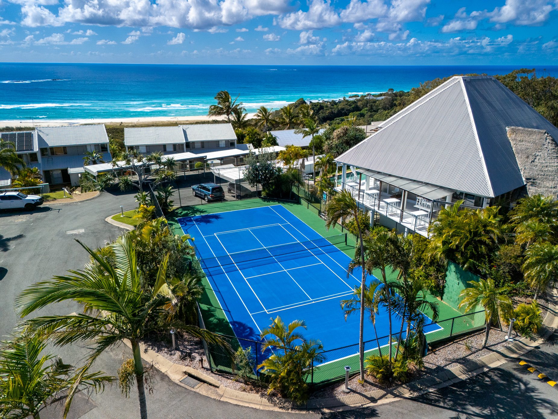 The tennis court among the palms at Pandanus Palms Resort, with the Coral Sea behind