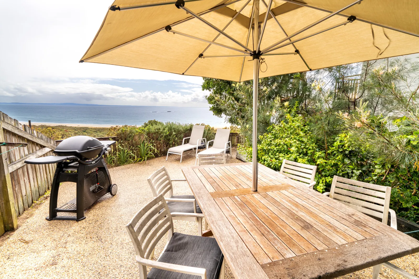 The private deck of a Premium Headland Ocean villa, with outdoor dining looking over the dunes to the ocean